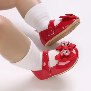 Close-up of shiny red patent baby girl princess shoes with a rhinestone bow detail