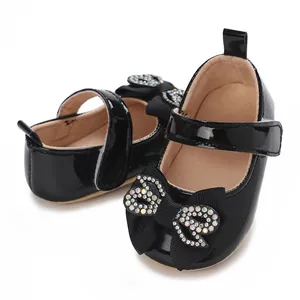 Detailed view of elegant black patent leather baby girl shoes with rhinestone bow accent