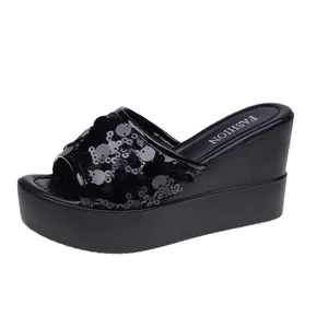 Detailed side view of elegant black sequined wedge slippers with thick platform sole