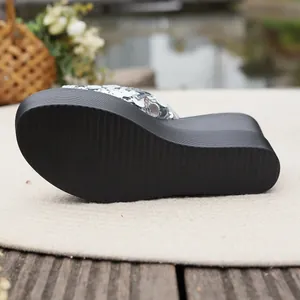 Close-up of the non-slip black sole and wedge heel of silver sequin slippers
