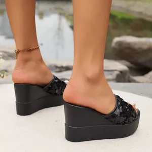Close-up of black platform wedge slippers featuring Mickey Mouse shaped sequins.