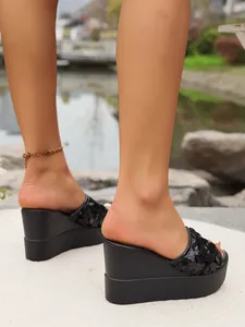 Detail of black sequined wedge slippers with a thick platform sole for women.