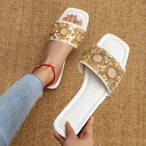 Detailopname van elegante witte platte sandalen met sprankelende gouden strass