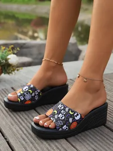 Detailed view of women's platform wedge sandals with Halloween skull and pumpkin patterns