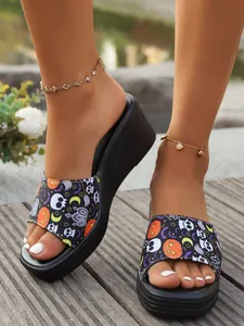 Close-up of women's wedge platform sandals featuring a vibrant Halloween skull and pumpkin print