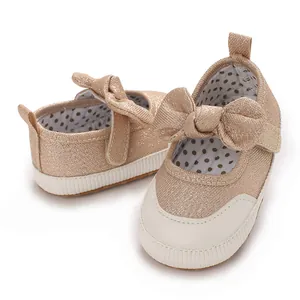 Macro view of glittery champagne baby walking shoes featuring a large bow detail