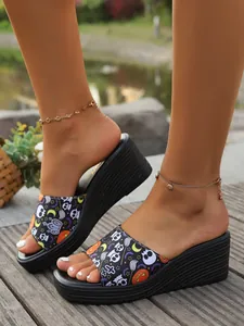 Close-up view of women's Halloween themed print wedge sandals on a wooden deck walkway