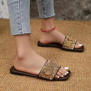 Close-up van platte slippers met vierkante neus en verfijnde strassversieringen.