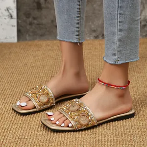 Close-up van elegante platte sandalen met vierkante neus en strass versieringen.