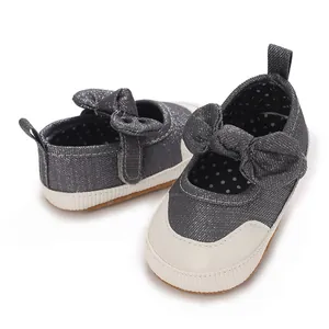Close-up of grey denim baby walking shoes with bow detail and white rubber toe cap
