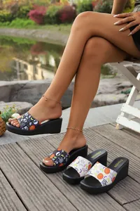 Detail view of platform wedge sandals featuring spooky Halloween pumpkin and skull prints