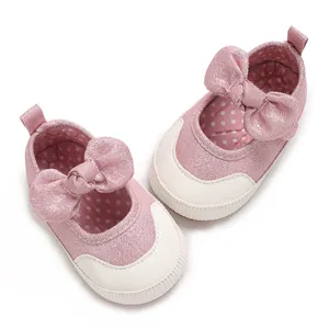 Close-up of pink baby soft sole walker shoes featuring a large bow and polka dot lining