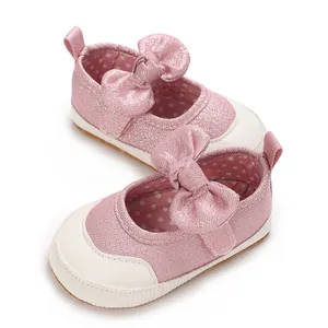 Close-up detail of pink glitter baby girl walking shoes with decorative bow