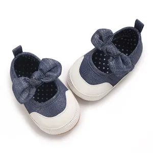 Detail view of navy blue baby pre-walker shoes with a large bow and soft white soles.