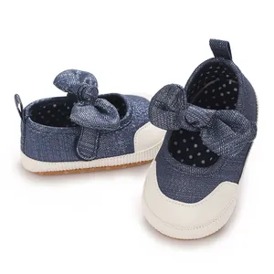 Close-up detail of infant girl walking shoes with large glittery denim bows and white soles