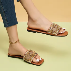 Detail van platte damessandalen met vierkante neus en glinsterende bandjes met strass