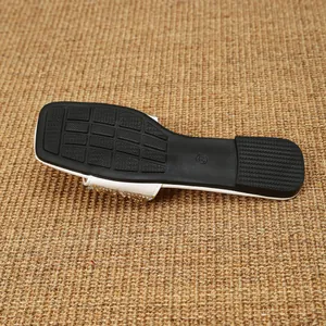 Detailweergave van de antislip zwarte zool van een witte sandaal met strass en vierkante teen.