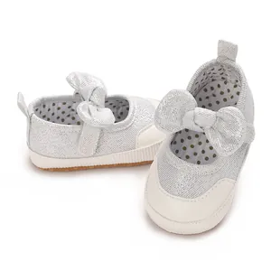 Close-up of sparkly silver baby walking shoes with bow details and polka dot lining.