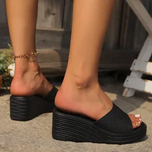 Primer plano de sandalias con cuña negras brillantes usadas al aire libre, suela con textura