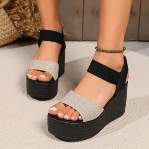Close-up of stylish beige linen and black strap wedge sandals on a circular woven rug