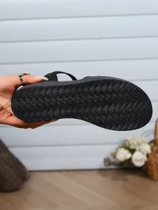 Close-up view of a black wedge sandal sole featuring a wavy anti-slip tread pattern