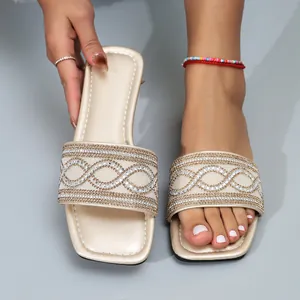 Detail van gouden platte slippers met vierkante neus en decoratieve strass-patronen