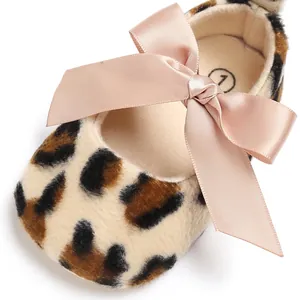 Vue rapprochée d'une chaussure léopard pour bébé avec un grand nœud en satin rose tendre