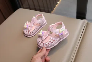 Dettaglio di sandali rosa per bambina con fiocco e decorazioni a mulino a vento