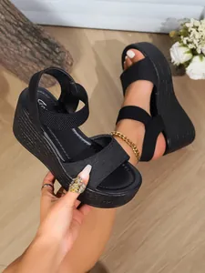 Close-up detail of black platform wedge sandals with elastic straps and textured sole