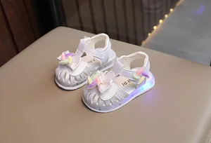 Dettaglio di sandali bianchi per bambina con suole a LED e decorazione a girandola