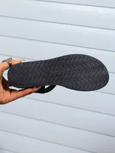 Detailed macro view showing the non-slip wavy texture on the outsole of black women's sandals
