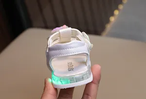 Dettaglio ravvicinato di sandali bianchi da bambina con suola luminosa a LED verde.