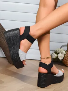 Close-up of women's black wedge sandals with textured platform and elastic straps.