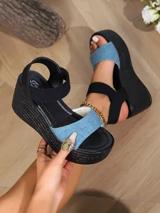 Detail view of denim fabric strap and black elastic buckle on platform wedge sandals