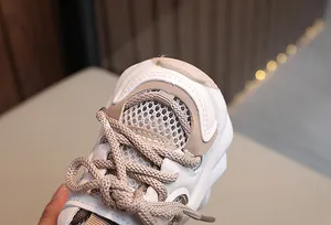 Detailed close-up showing the breathable mesh texture and laces of children's white sneakers