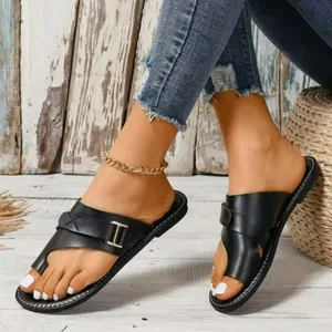 Detailansicht stilvoller flacher Zehensteg-Sandalen aus schwarzem Leder am Fuß