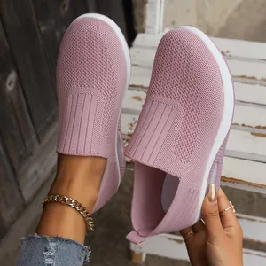 Detail of pink fly-knit slip-on walking shoes with air cushion sole on wooden slats