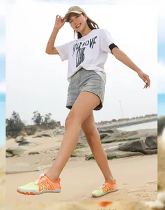 Zapatos de agua de secado rápido naranjas y verdes usados por una modelo en la playa