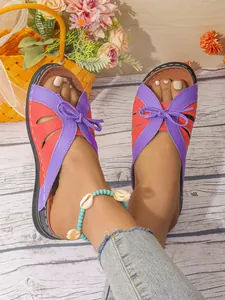 Gros plan de sandales de plage d'été vibrantes pour femmes en violet et orange avec noeud