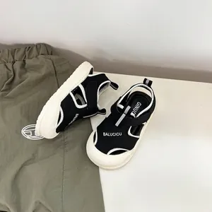 Vista dall'alto di sandali chiusi in bianco e nero per bambini piccoli con dettaglio logo