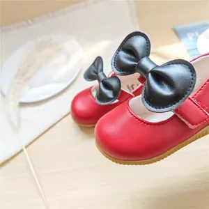 Nahaufnahme von roten Prinzessinnenschuhen für Kleinkinder mit eleganten schwarzen Schleifen.