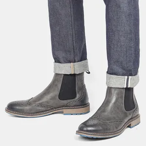 Primer plano de botines Chelsea Brogue grises vintage para hombre con detalles clásicos.