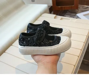 Close-up of black sequined girls' canvas Mary Janes with velcro strap and thick sole.