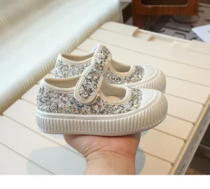 Detailed view of fashionable silver sequined girl's Mary Jane shoes with Velcro strap.