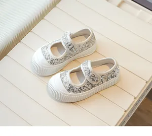 Detailed view of white girls' canvas shoes featuring silver sequins and velcro straps