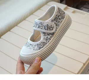 Detailed close-up of girls' sparkling silver sequin canvas shoes with convenient Velcro strap