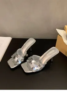 Close-up shot of elegant silver high-heeled sandals featuring shimmering sequin details for women