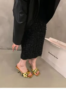 Stylish model wearing golden sequined high-heel mules with a chic square toe.