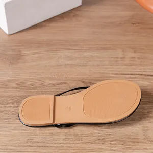 Detail view of a black women's flip-flop featuring a textured non-slip sole in tan.