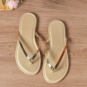 Detailed view of women's champagne gold metallic flip-flop sandals on wood